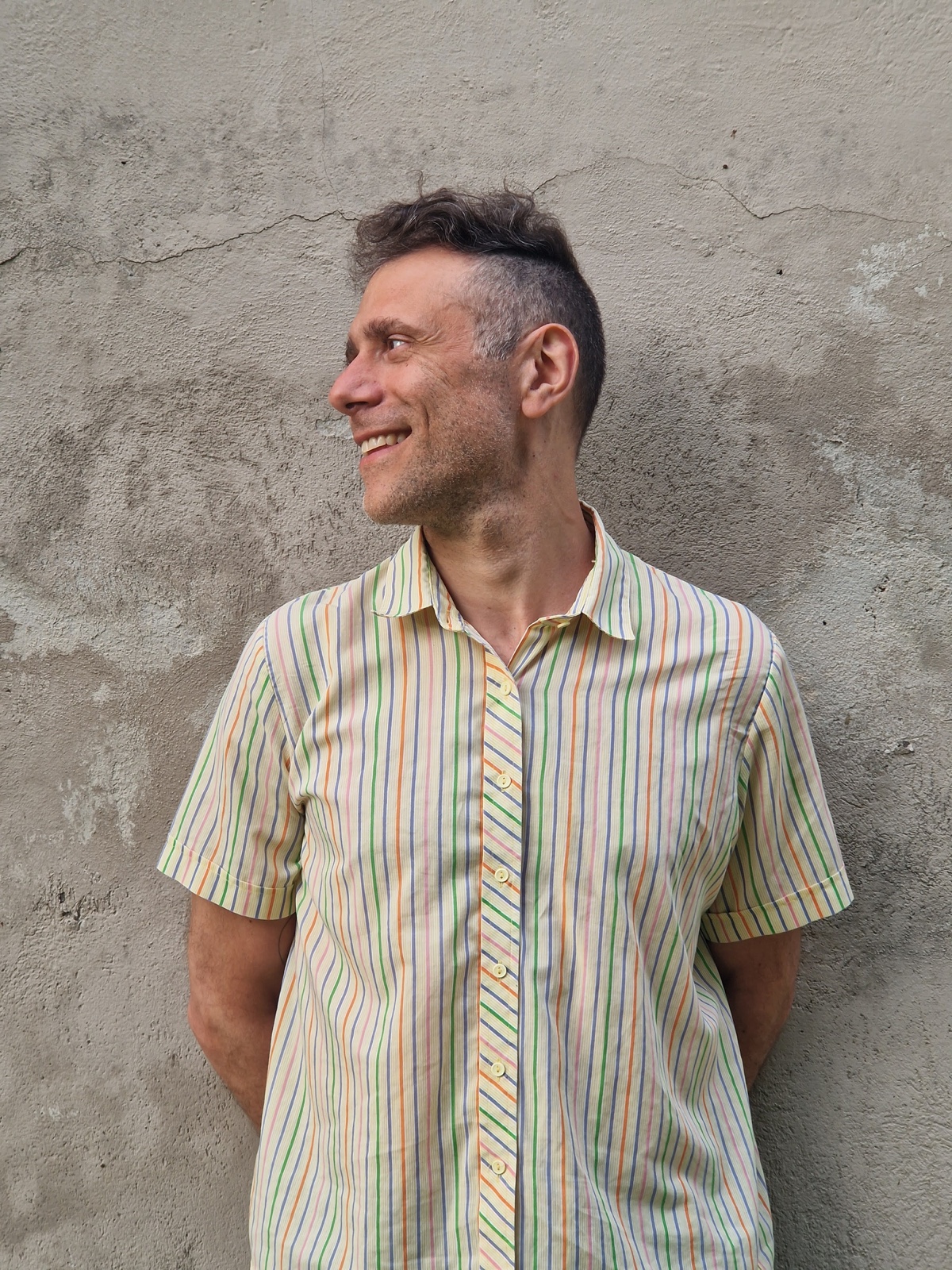 Portrait of Roberto standing beside a textured wall
